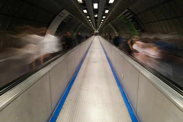 A Blurry Photo Of People Riding On An Escalator
