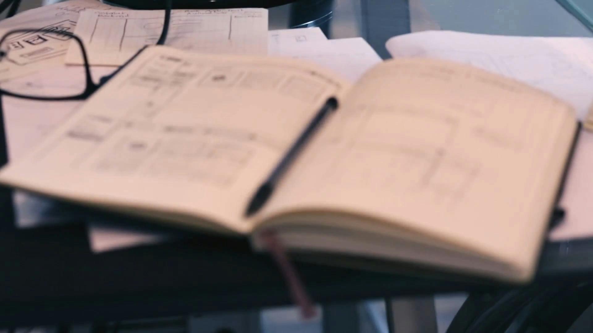 An Open Notebook Filled With Doodles And Schematics Accompanied By A Pen.