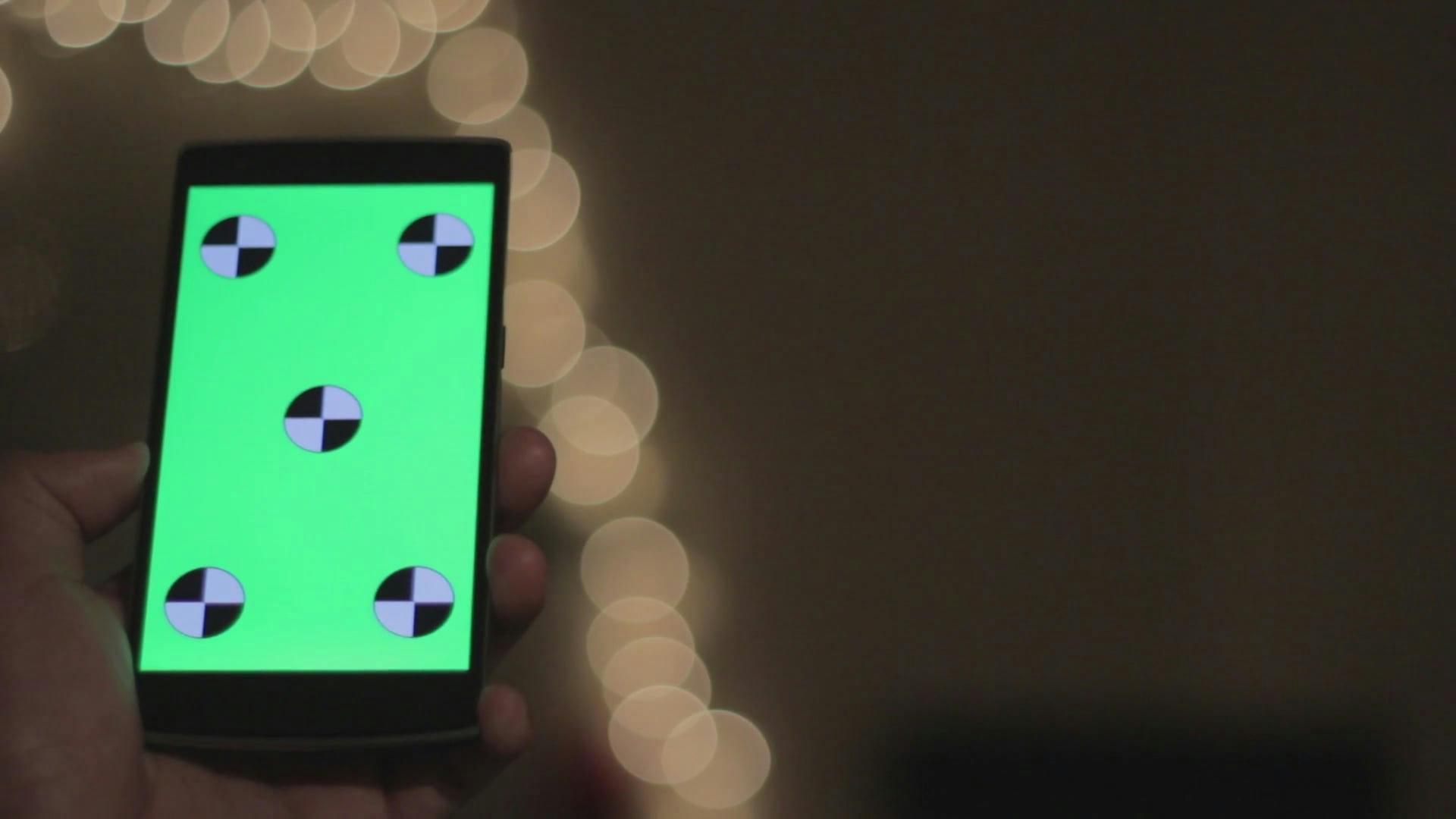 Hand Holds Smartphone With Green Screen For Chroma Key Replacement.